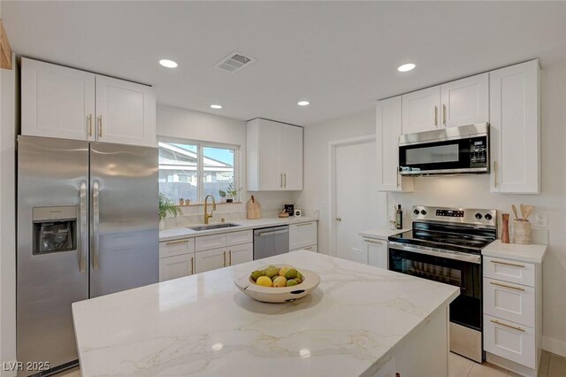 5904 Apple Valley Ln, Las Vegas, NV 89108 - kitchen with appliances with stainless steel finishes, a sink, white cabinets, light stone counters, and recessed lighting