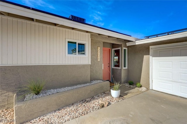 doorway to property with a garage, stucco siding, and driveway