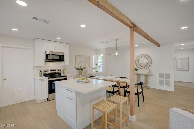 kitchen featuring light wood-style flooring, stainless steel appliances, white cabinetry, and visible vents