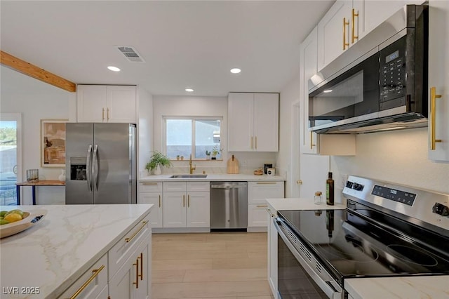 5904 Apple Valley Ln, Las Vegas, NV 89108 - kitchen featuring appliances with stainless steel finishes, plenty of natural light, white cabinetry, light stone countertops, and recessed lighting