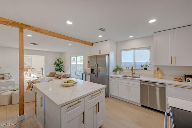 5904 Apple Valley Ln, Las Vegas, NV 89108 - kitchen with appliances with stainless steel finishes, open floor plan, a sink, white cabinets, and a kitchen island