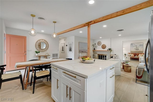 kitchen with visible vents, a kitchen island, light stone countertops, recessed lighting, and white cabinetry