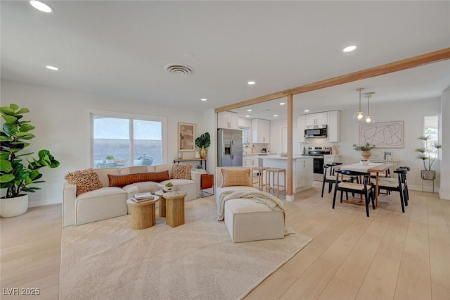 living room featuring recessed lighting, light wood-type flooring, and visible vents
