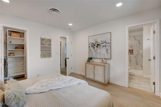 bedroom with a walk in closet, visible vents, baseboards, light wood-style floors, and recessed lighting