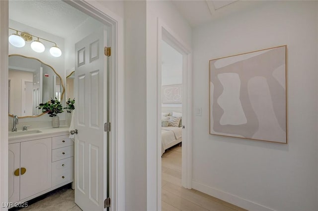 corridor featuring baseboards and a sink