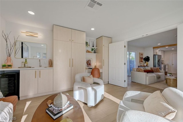 living area featuring light wood-style floors, beverage cooler, recessed lighting, indoor bar, and visible vents