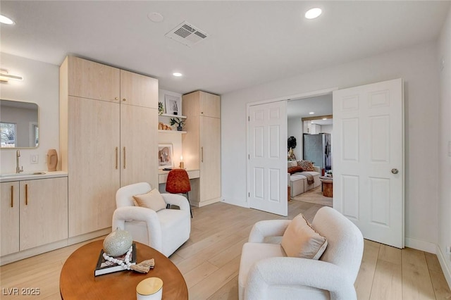 living area with recessed lighting, baseboards, visible vents, and light wood-type flooring