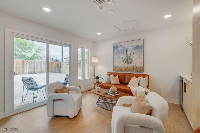 living area with baseboards, visible vents, attic access, and light wood-type flooring