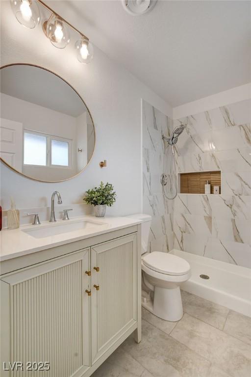 full bath with a marble finish shower, vanity, and toilet