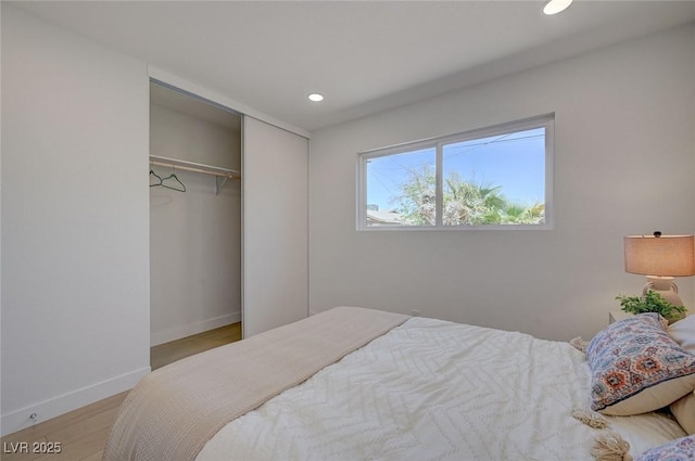 bedroom with baseboards, light wood-type flooring, a closet, and recessed lighting