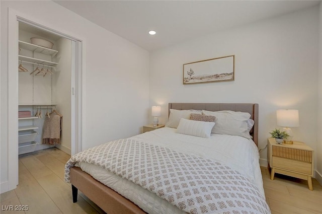 bedroom featuring a closet, baseboards, a walk in closet, recessed lighting, and light wood finished floors