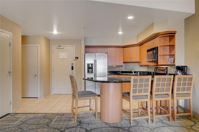 kitchen featuring open shelves, a peninsula, dark countertops, a sink, and appliances with stainless steel finishes