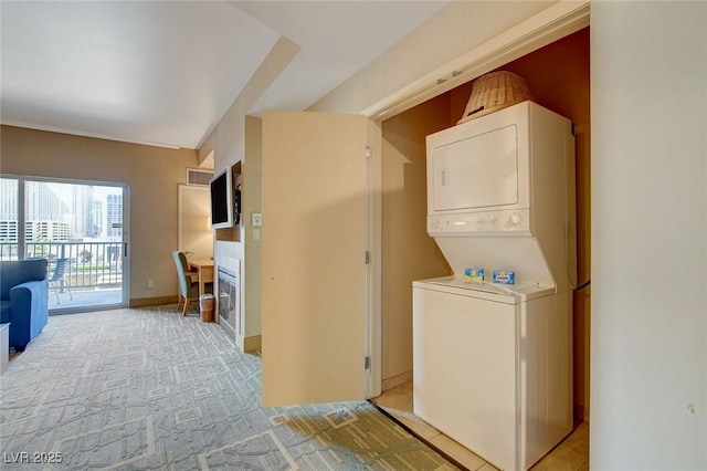 laundry area featuring laundry area, stacked washer / dryer, and light colored carpet