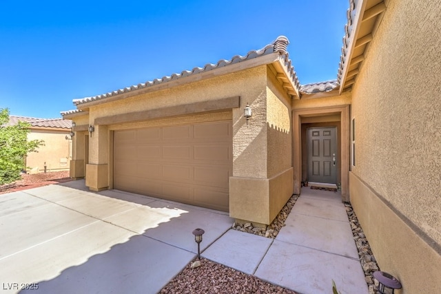 view of front of property with an attached garage, stucco siding, driveway, and a tile roof