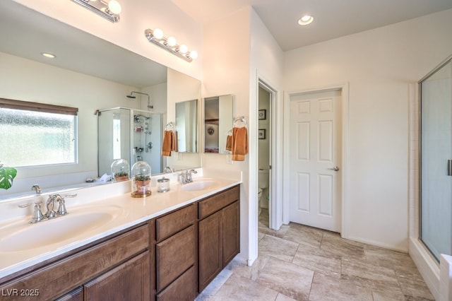 bathroom featuring toilet, a shower stall, and a sink