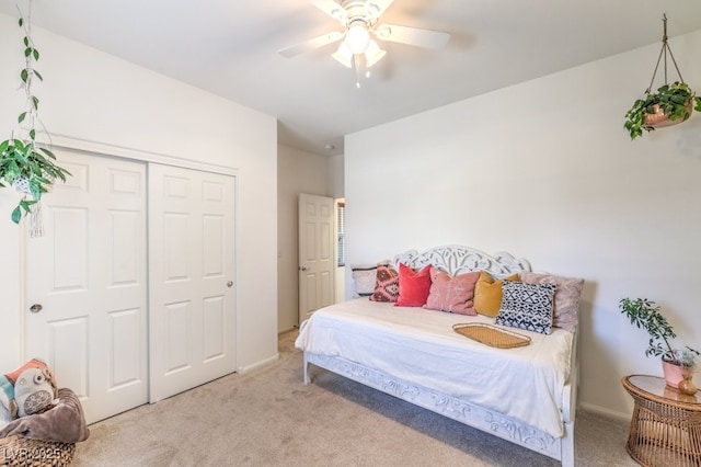 bedroom with baseboards, a ceiling fan, a closet, and light colored carpet