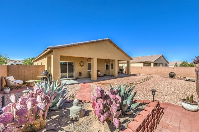 rear view of house featuring a fenced backyard, a patio, and stucco siding
