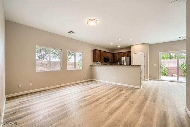 unfurnished living room featuring baseboards, light wood-type flooring, and visible vents