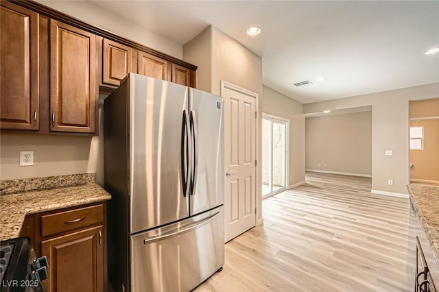 kitchen featuring light wood-style floors, range with electric cooktop, plenty of natural light, freestanding refrigerator, and visible vents