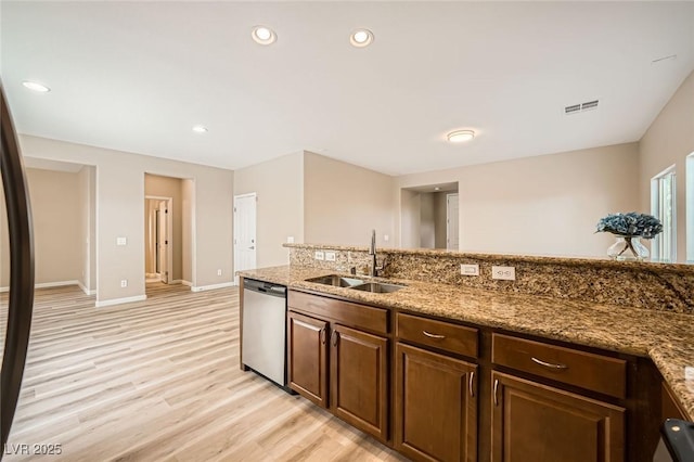kitchen with a sink, light wood-style floors, baseboards, stainless steel dishwasher, and visible vents