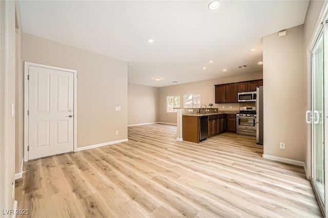kitchen featuring appliances with stainless steel finishes, baseboards, light wood-type flooring, and open floor plan