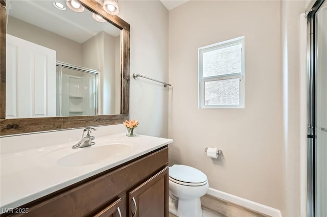 full bath featuring a shower stall, wood finished floors, vanity, baseboards, and toilet