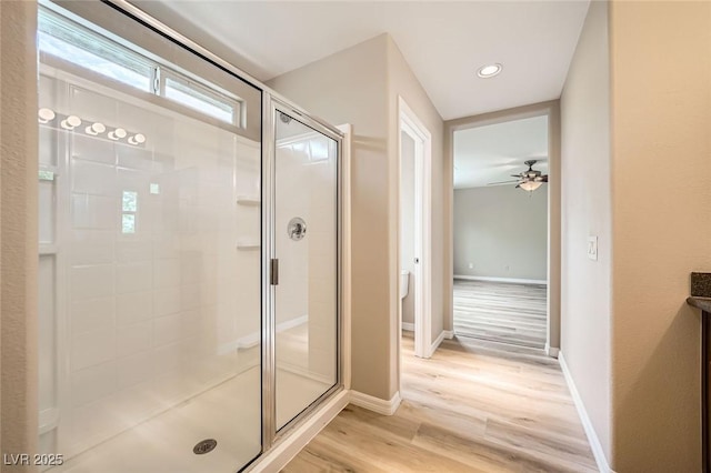 bathroom featuring ceiling fan, a stall shower, wood finished floors, baseboards, and recessed lighting