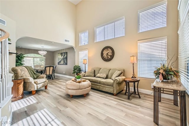 living room featuring light wood-style floors, arched walkways, baseboards, and visible vents