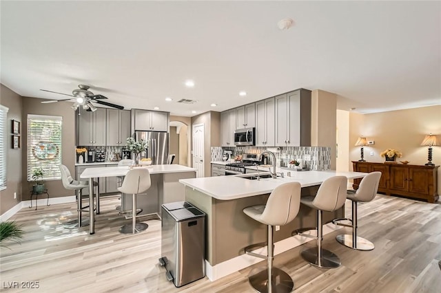 kitchen with gray cabinetry, appliances with stainless steel finishes, a breakfast bar area, and light countertops