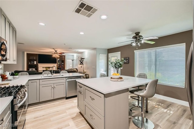 kitchen with ceiling fan, visible vents, appliances with stainless steel finishes, a sink, and a breakfast bar