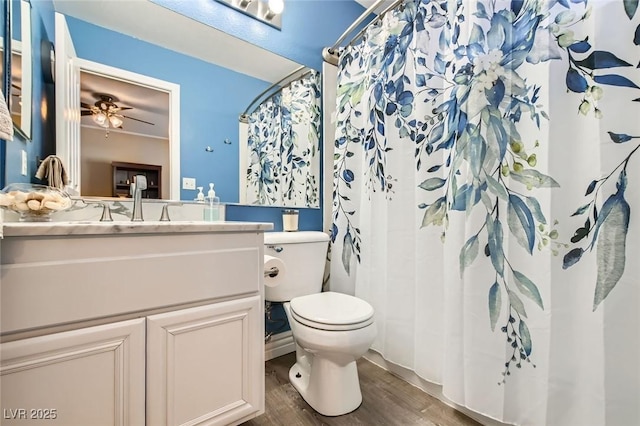 full bath featuring vanity, wood finished floors, toilet, ceiling fan, and a shower with curtain