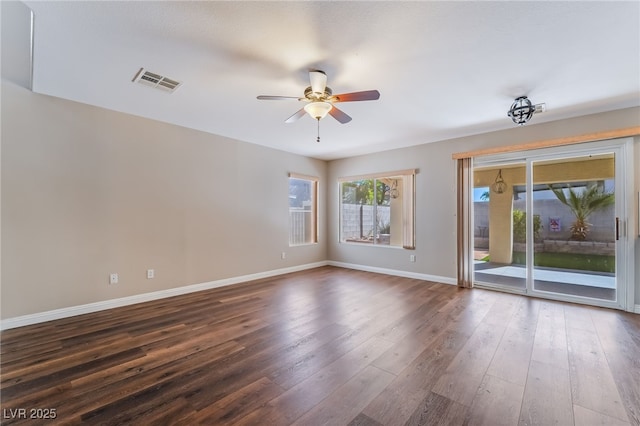 empty room featuring a ceiling fan, baseboards, visible vents, and dark wood-type flooring