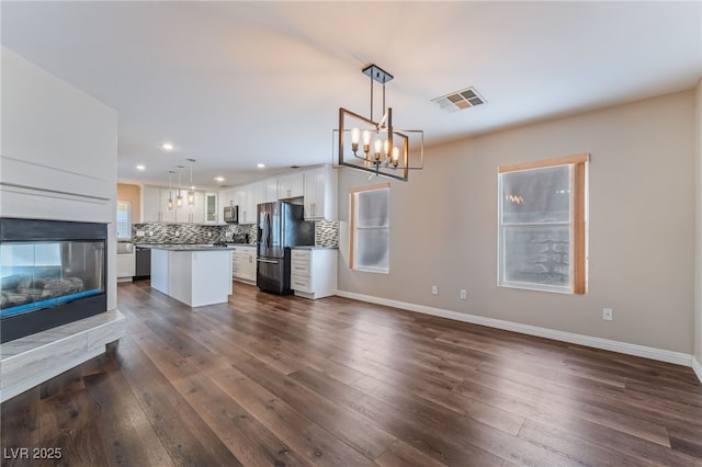 kitchen featuring visible vents, dark wood-type flooring, a center island, white cabinetry, and refrigerator with ice dispenser