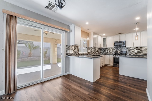 kitchen featuring stainless steel range with gas cooktop, white cabinets, visible vents, and dark countertops