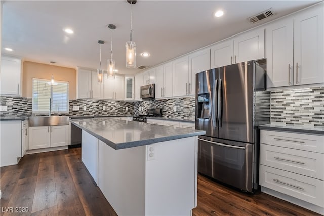 kitchen featuring stainless steel appliances, visible vents, decorative backsplash, and a sink