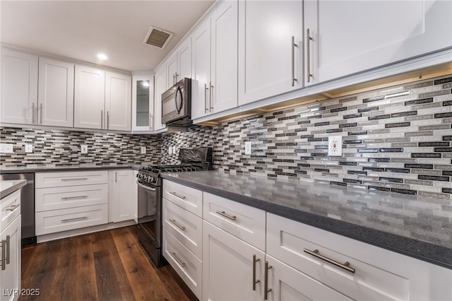 kitchen with white cabinets, backsplash, gas range oven, and visible vents