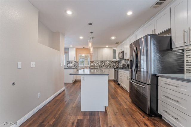 kitchen with visible vents, decorative backsplash, a kitchen island, white cabinets, and stainless steel appliances