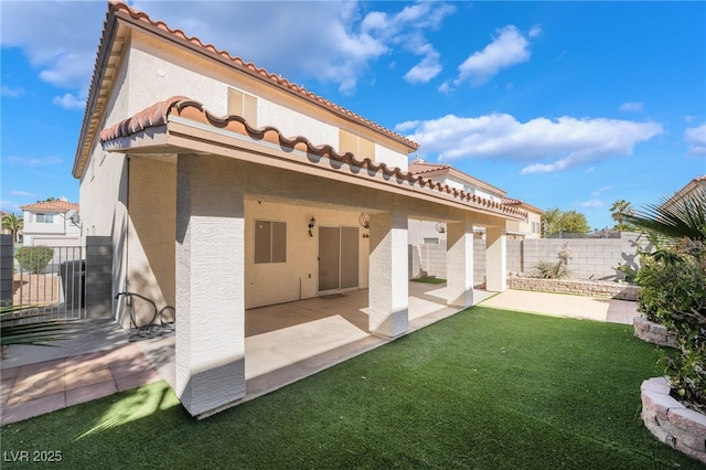 rear view of property with a tile roof, stucco siding, a lawn, a patio, and fence private yard