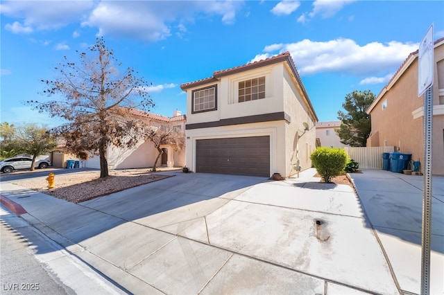 view of front of home featuring fence, an attached garage, a tile roof, stucco siding, and driveway