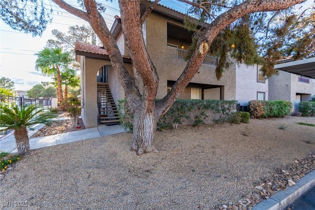 exterior space featuring a tiled roof, stairs, and stucco siding