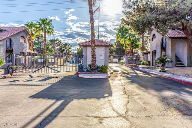 view of road with a gated entry, a gate, and curbs