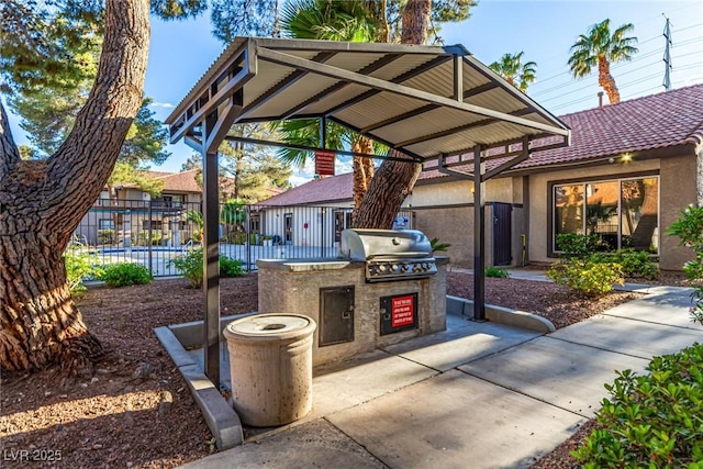 view of patio / terrace featuring exterior kitchen, fence, and a grill
