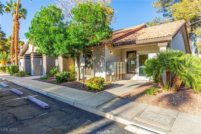 view of front of home with uncovered parking, a tile roof, and stucco siding