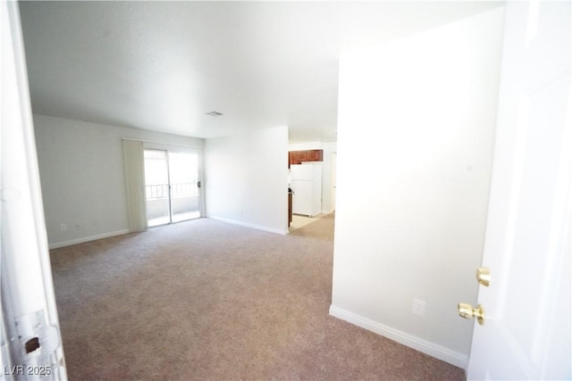 empty room featuring baseboards and light colored carpet
