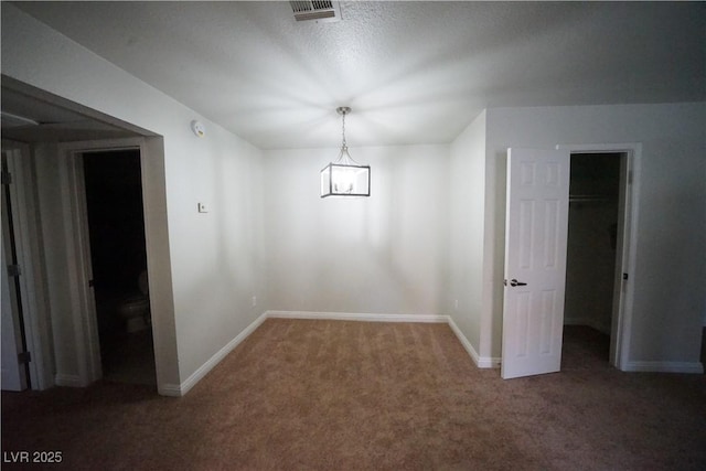 unfurnished dining area with carpet floors, a notable chandelier, baseboards, and visible vents