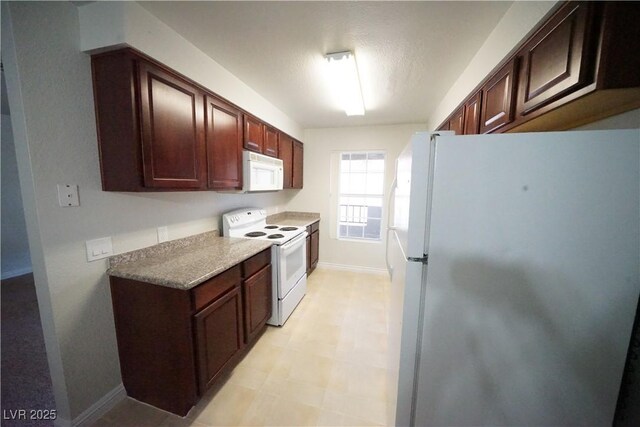 kitchen with baseboards, light countertops, light floors, and white appliances