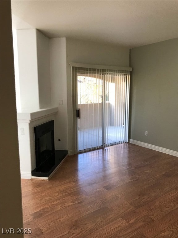 unfurnished living room featuring baseboards, a glass covered fireplace, and wood finished floors