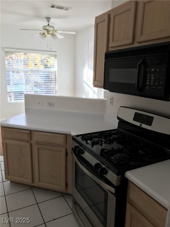 kitchen featuring ceiling fan, black microwave, stainless steel range with gas cooktop, light tile patterned floors, and visible vents
