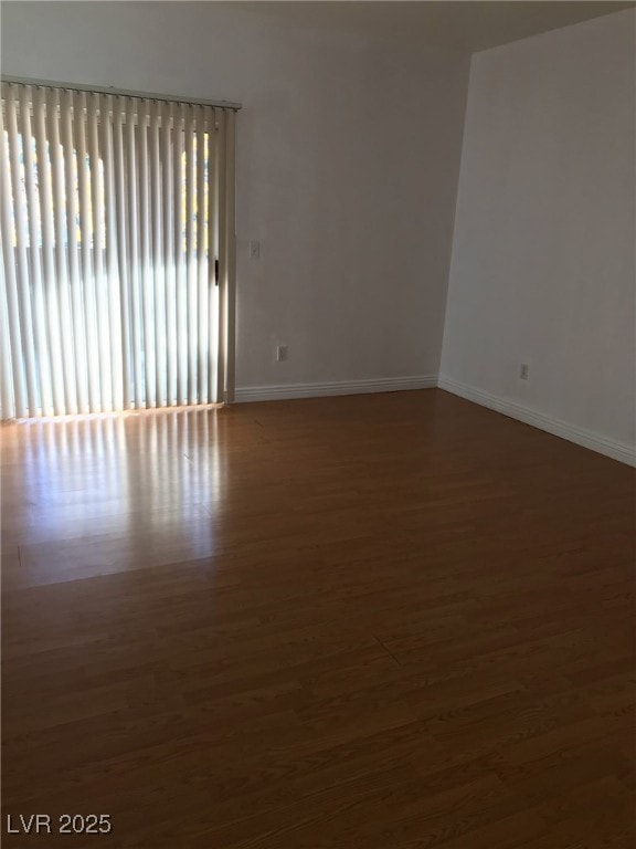 empty room with baseboards and wood finished floors