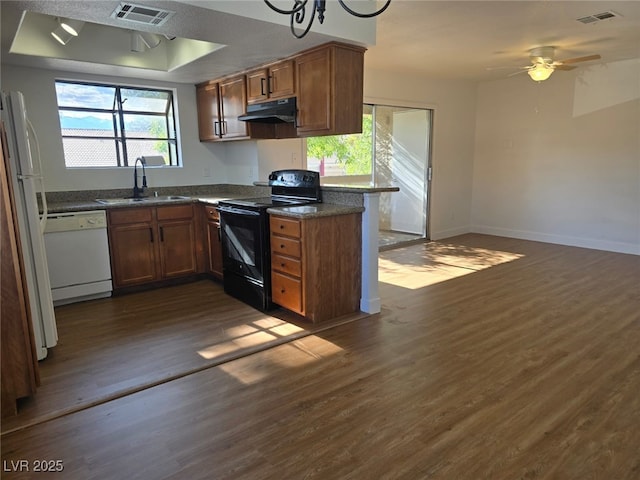 kitchen featuring white appliances, under cabinet range hood, visible vents, and a sink